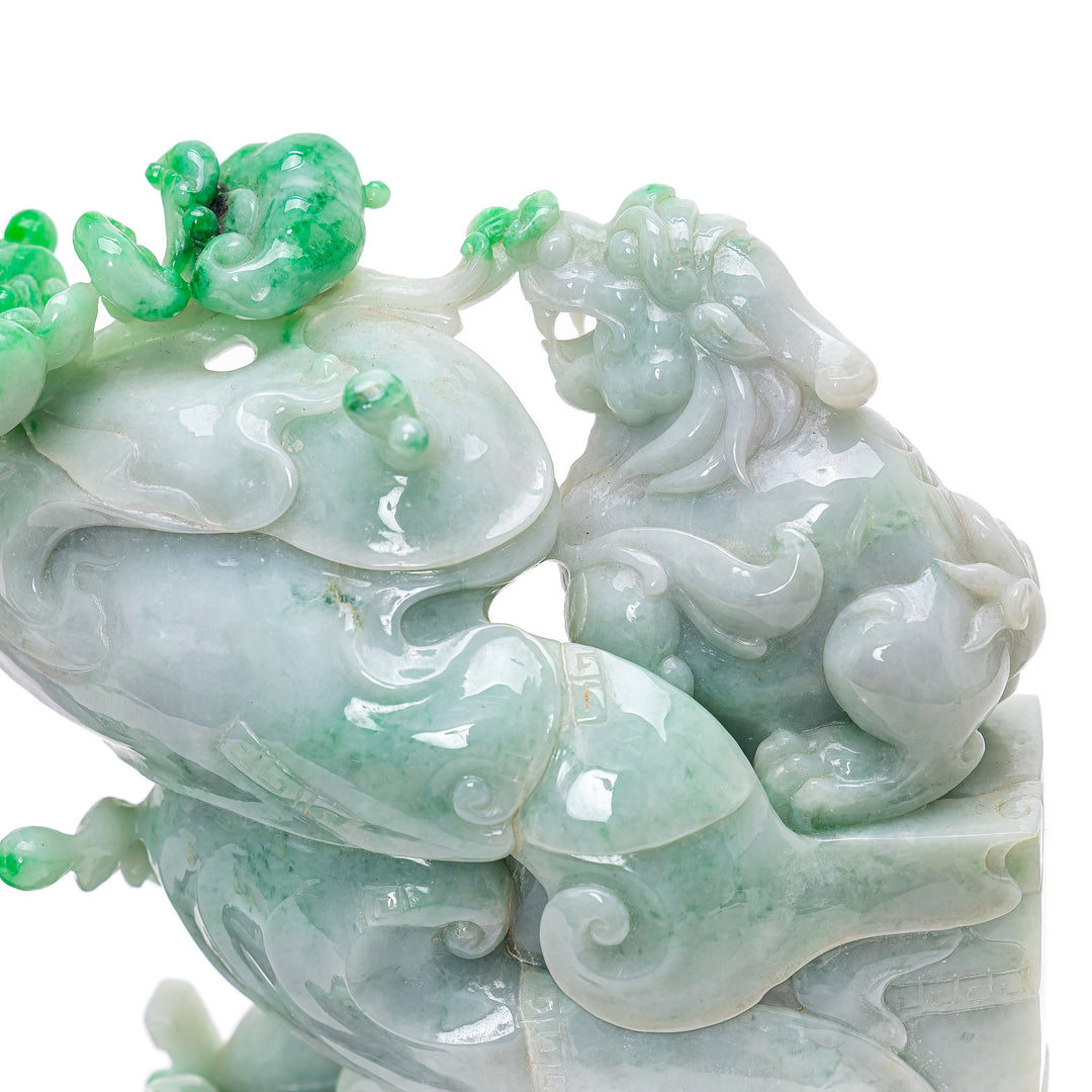 Pale apple and lavender jade lions on detailed mahogany platforms.
