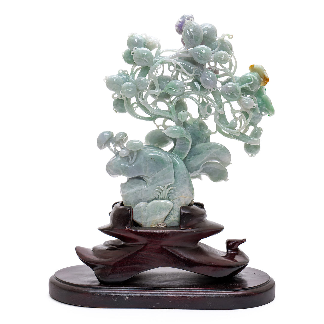 Artistic jade sculpture with bird perched on branches.
