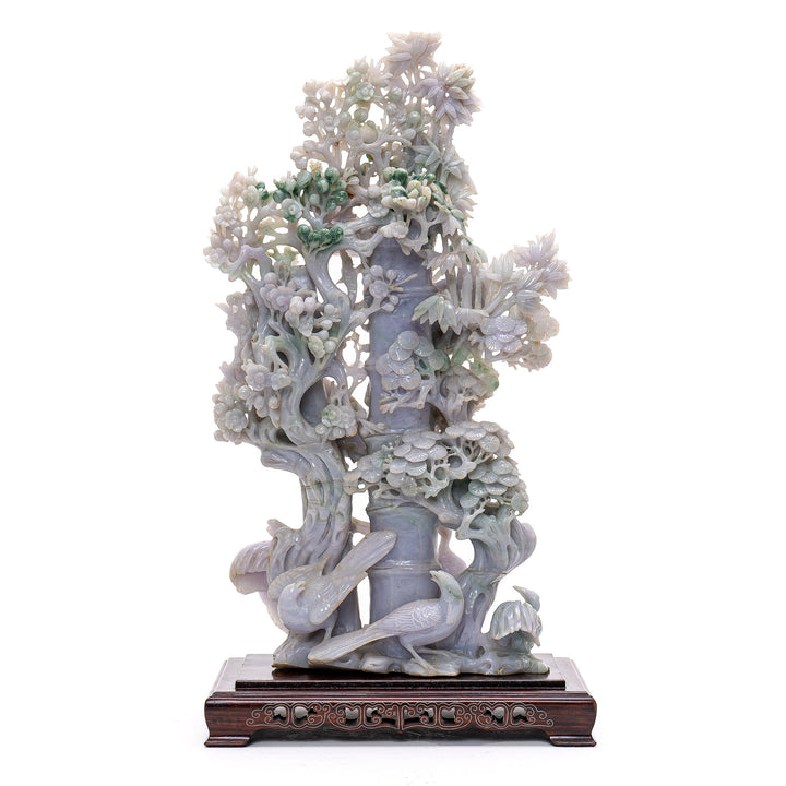 Handcrafted jade artwork illustrating cranes frolicking amidst lush pine foliage.
