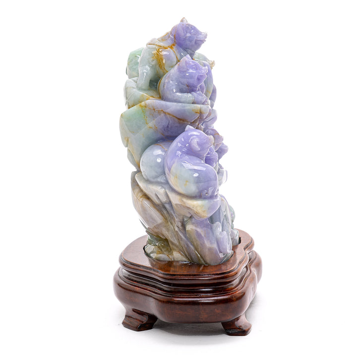Detailed jade sculpture illustrating the playful interaction of pigs on a lush mountainside.