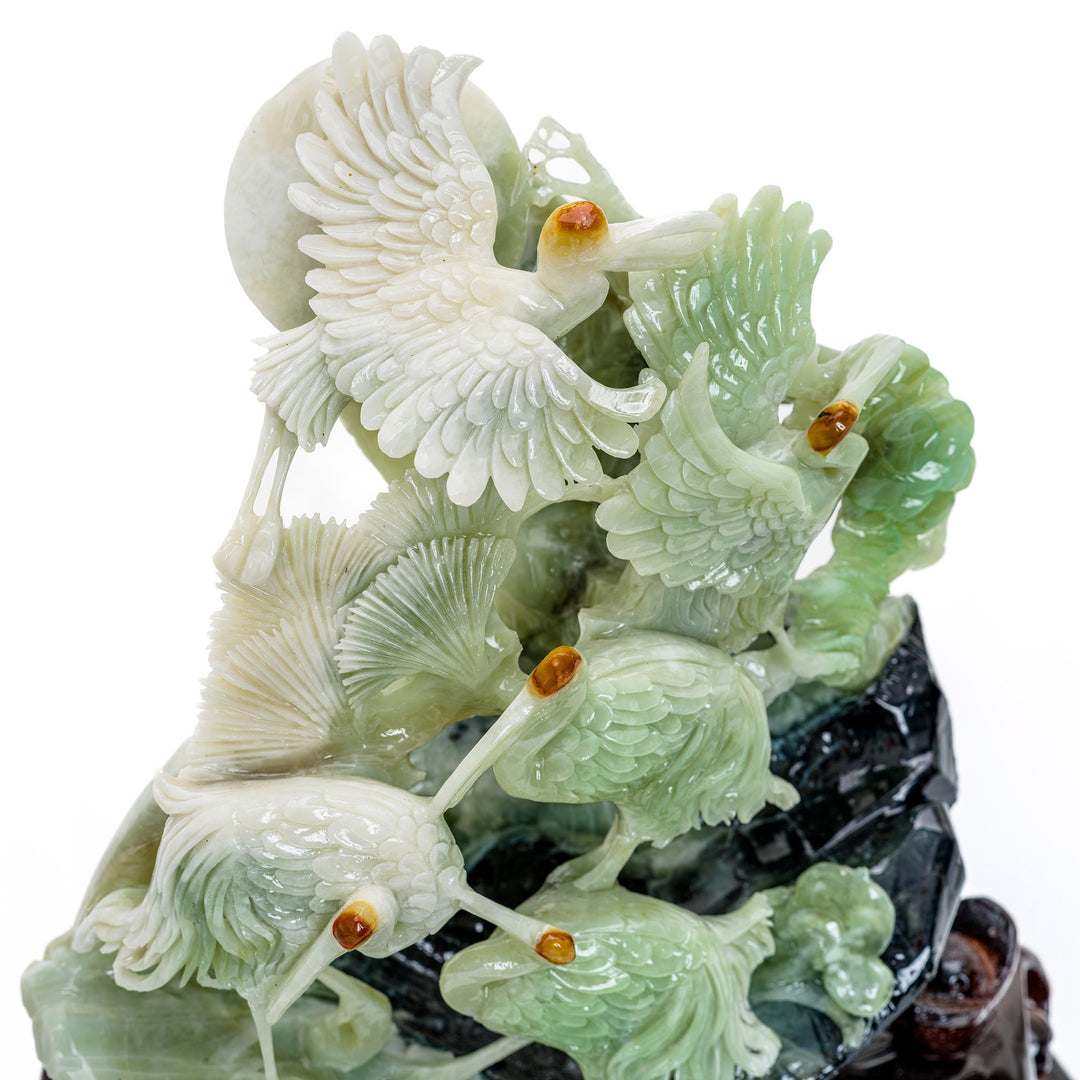 Grouping of cranes in agate, hand-carved on a lush hillside.