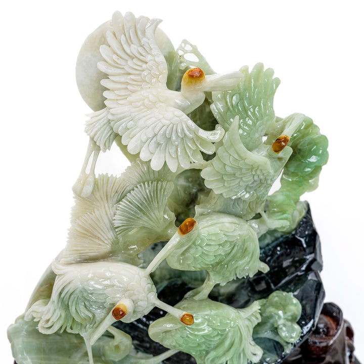 Grouping of cranes in agate, hand-carved on a lush hillside.