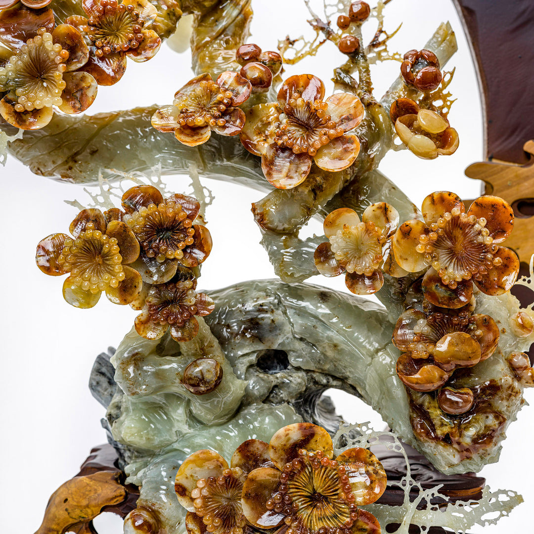 Artisanal peony branch carving in translucent agate on a display stand.