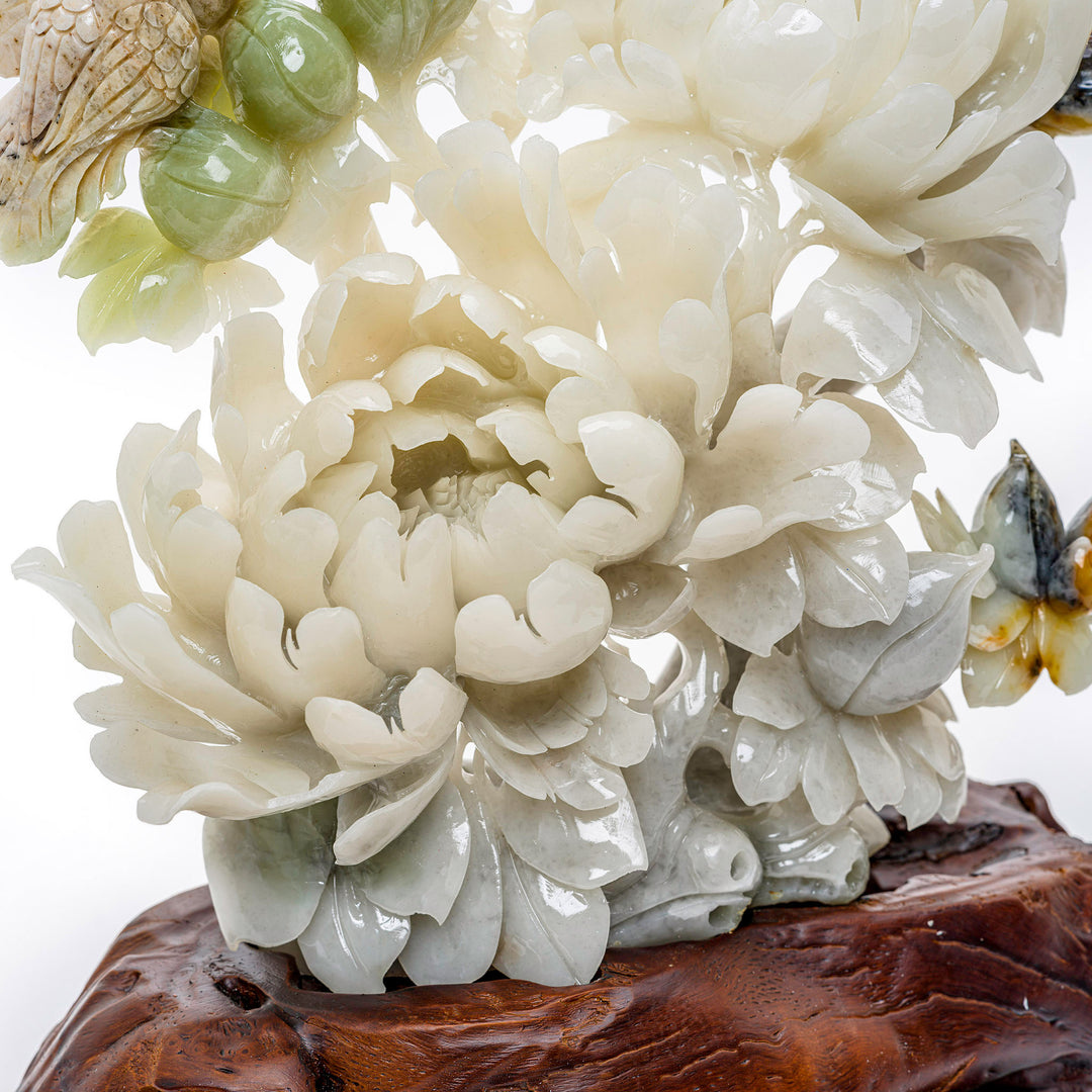 Delicate bird perched on blooming peonies carved from agate on a wooden base.