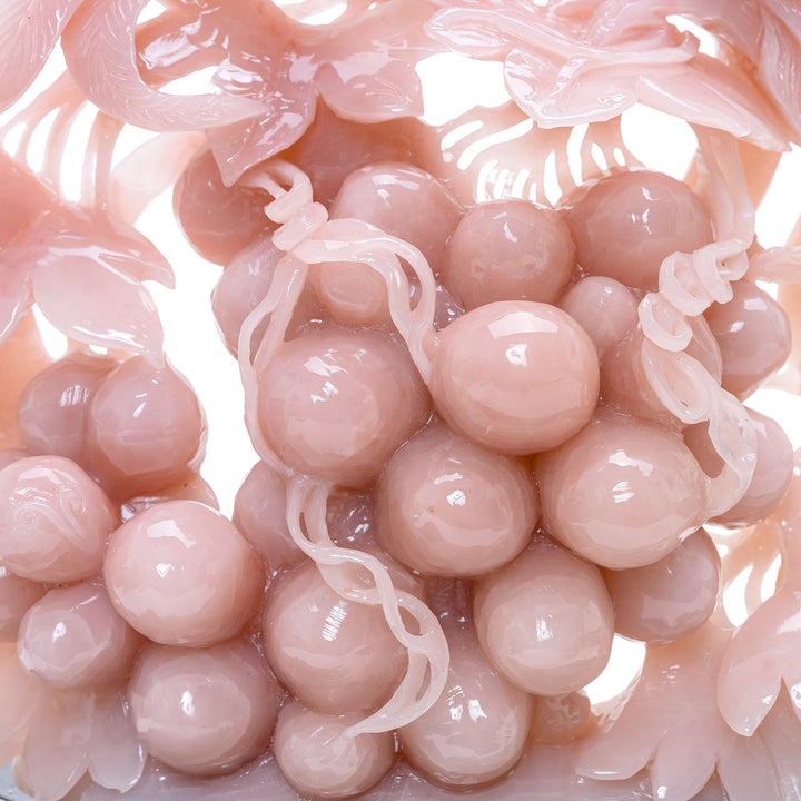 Symbolic rose quartz sculpture with phoenix birds, mounted on intricately carved wood