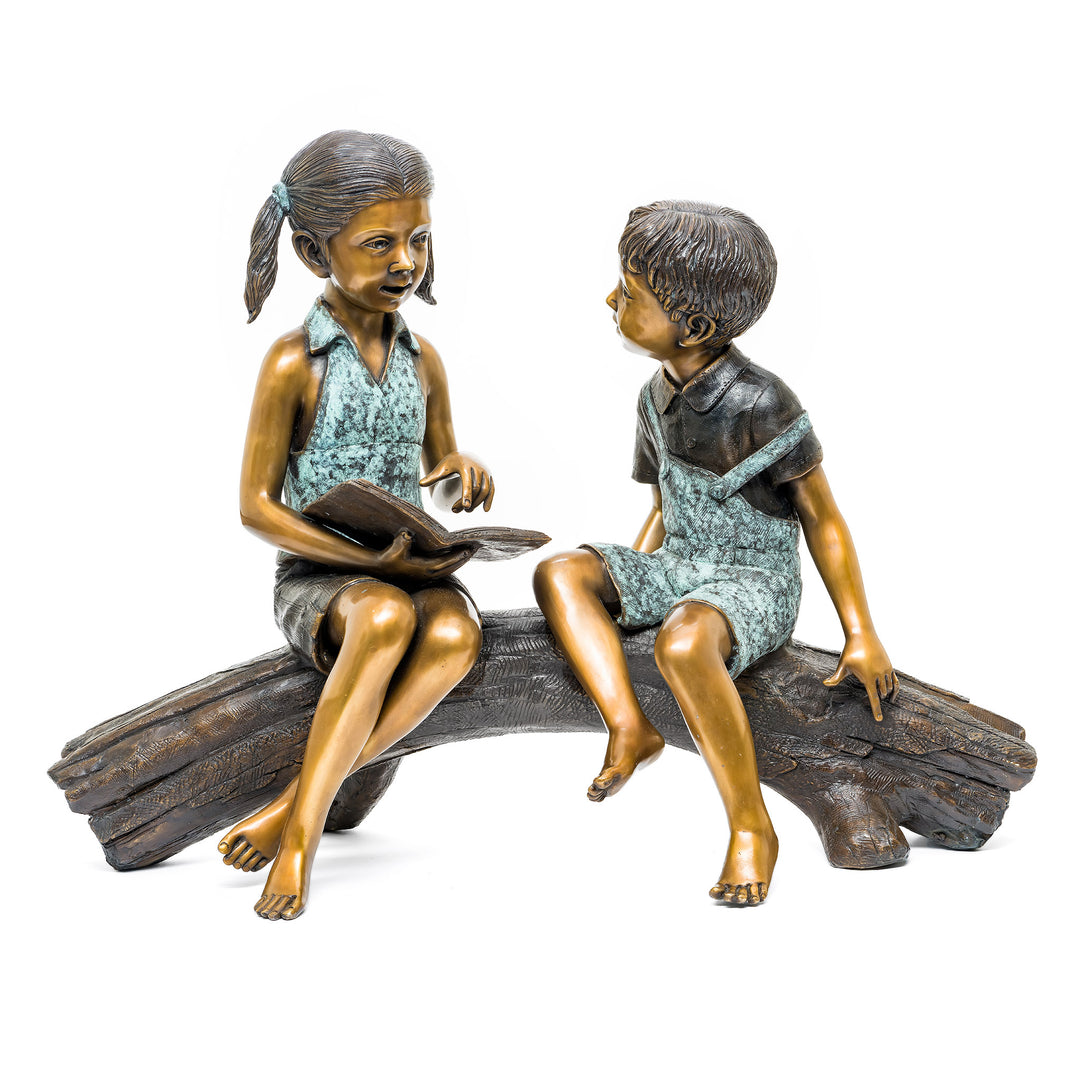 Bronze brother and sister reading sculpture on a log