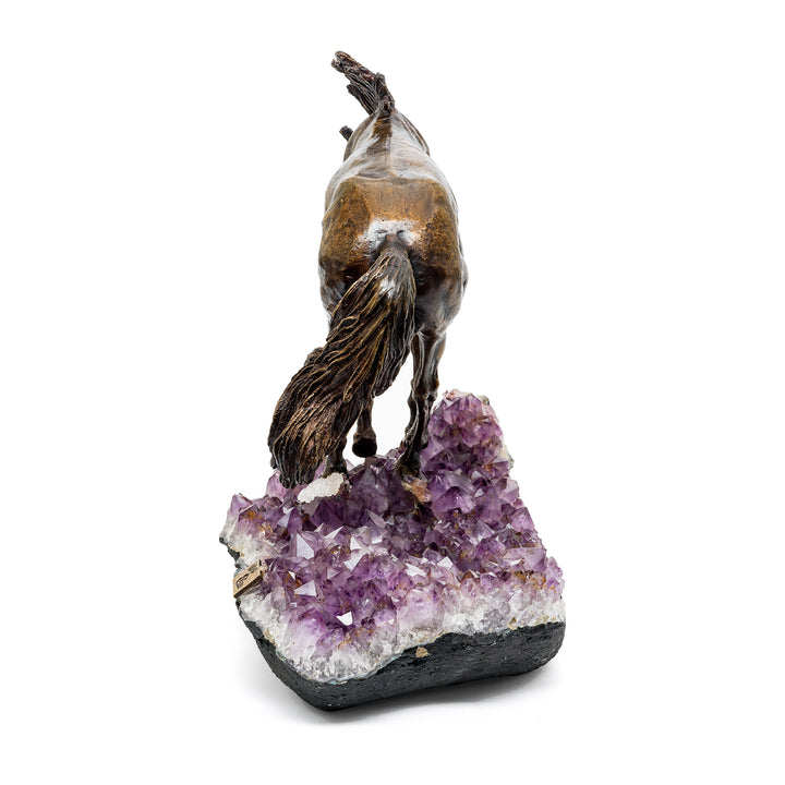 Rear view of bronze horse with raised tail over crystal base