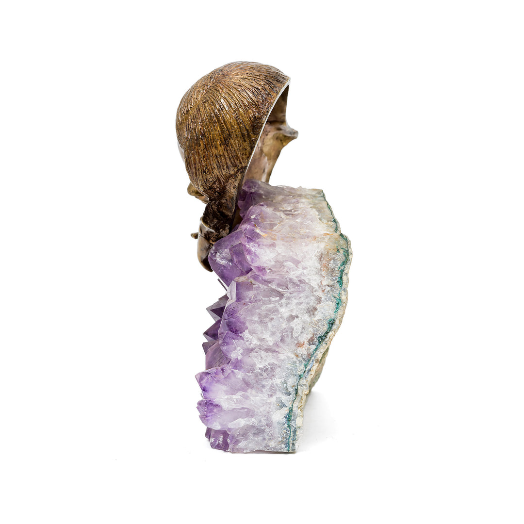 Side angle of bronze woman’s head resting on hands above crystal