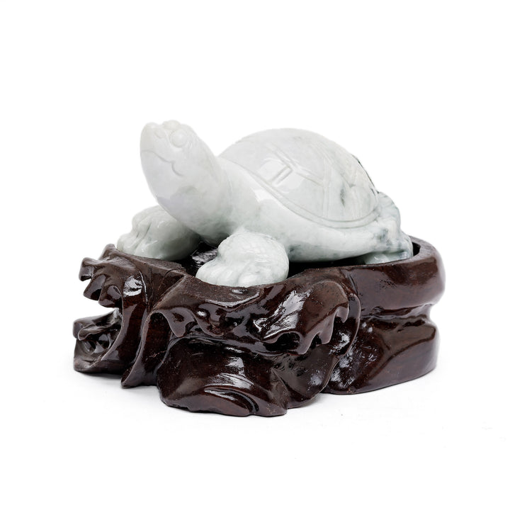 Small jade turtle sculpture on carved wood base