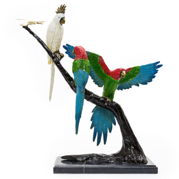 All-bronze sculpture of parrots and a hummingbird on a tree capturing avian grace