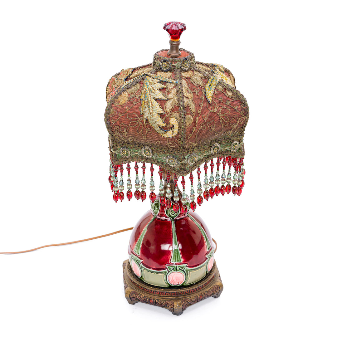 Handcrafted table lamp with ornate bronze base and beaded details.