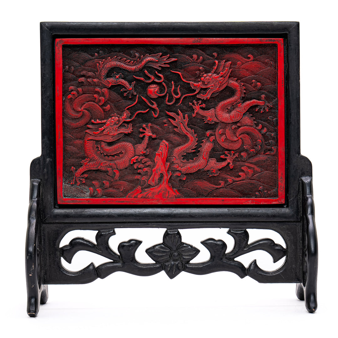 Intricate hand-carved cinnabar screen depicting dragons in pursuit of enlightenment.