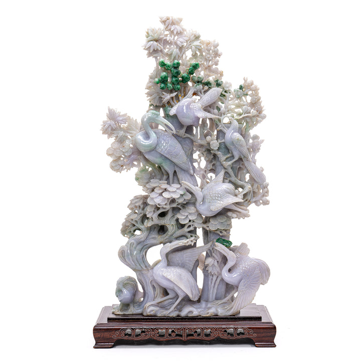 Elegant jade sculpture depicting playful cranes amongst vibrant pine trees.