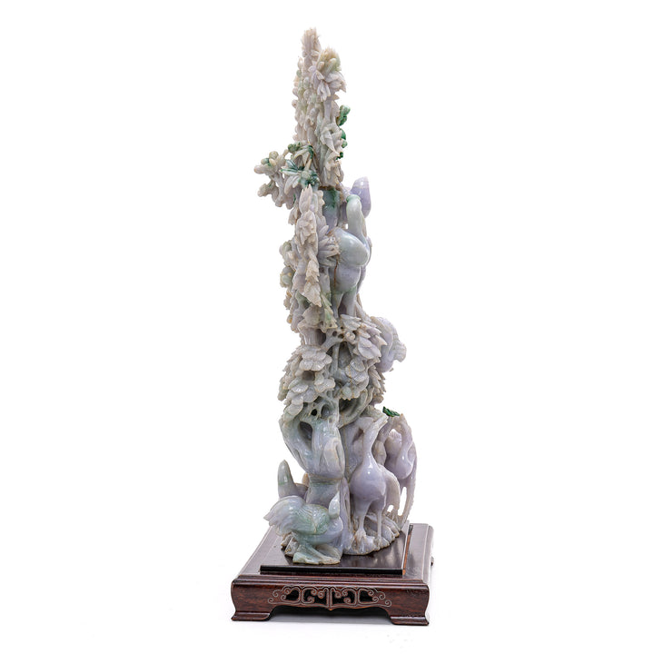 Refined jade sculpture portraying the harmonious dance of cranes and pine trees.