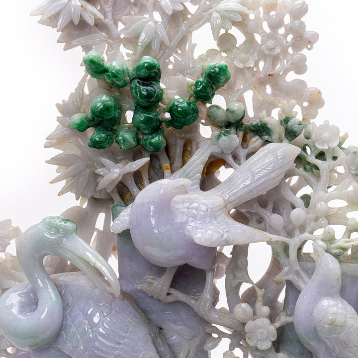 Artful jade piece showcasing cranes amidst pine, a symbol of happiness and fortitude.