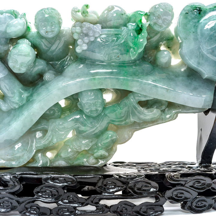 Enchanted display of jade children with a scepter on a carved base.