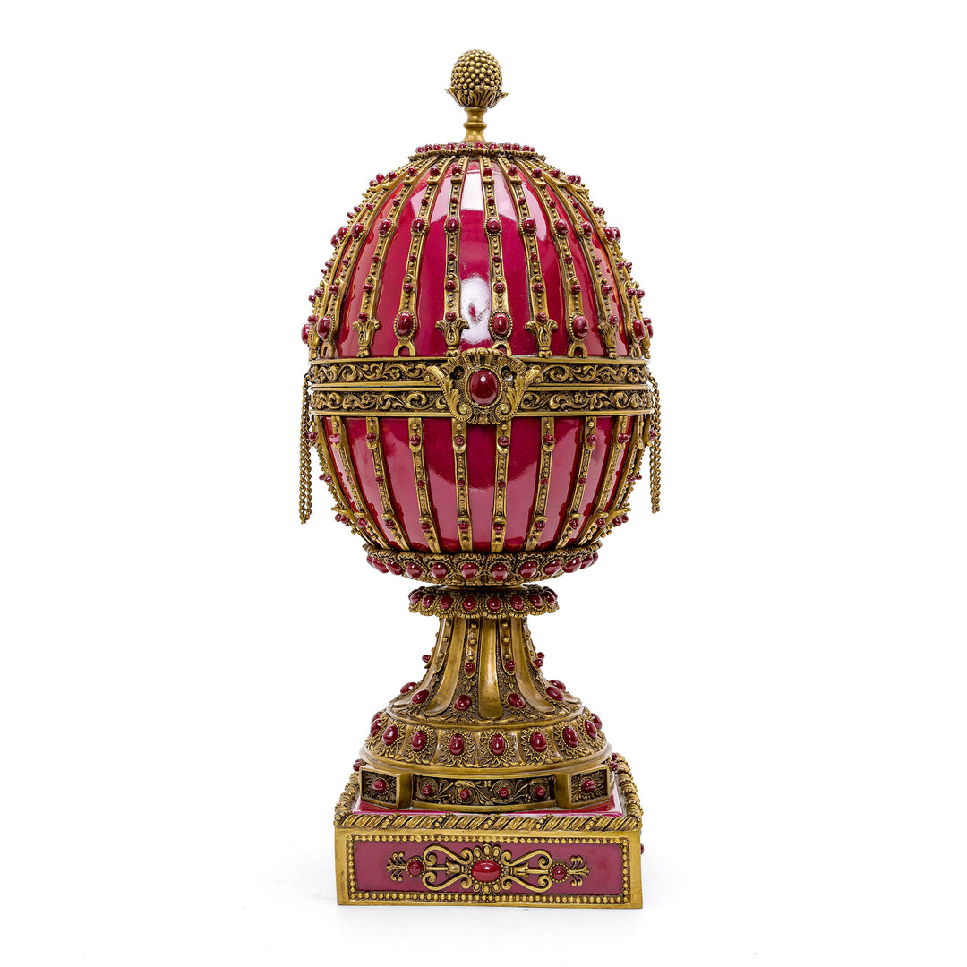 Red porcelain egg with doré bronze accents and cabochons on a pedestal base.