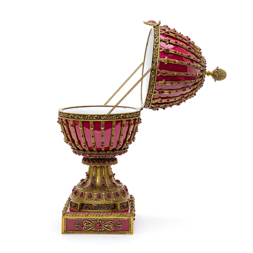 Imperial red porcelain egg adorned with bronze detailing and mounted on a base.