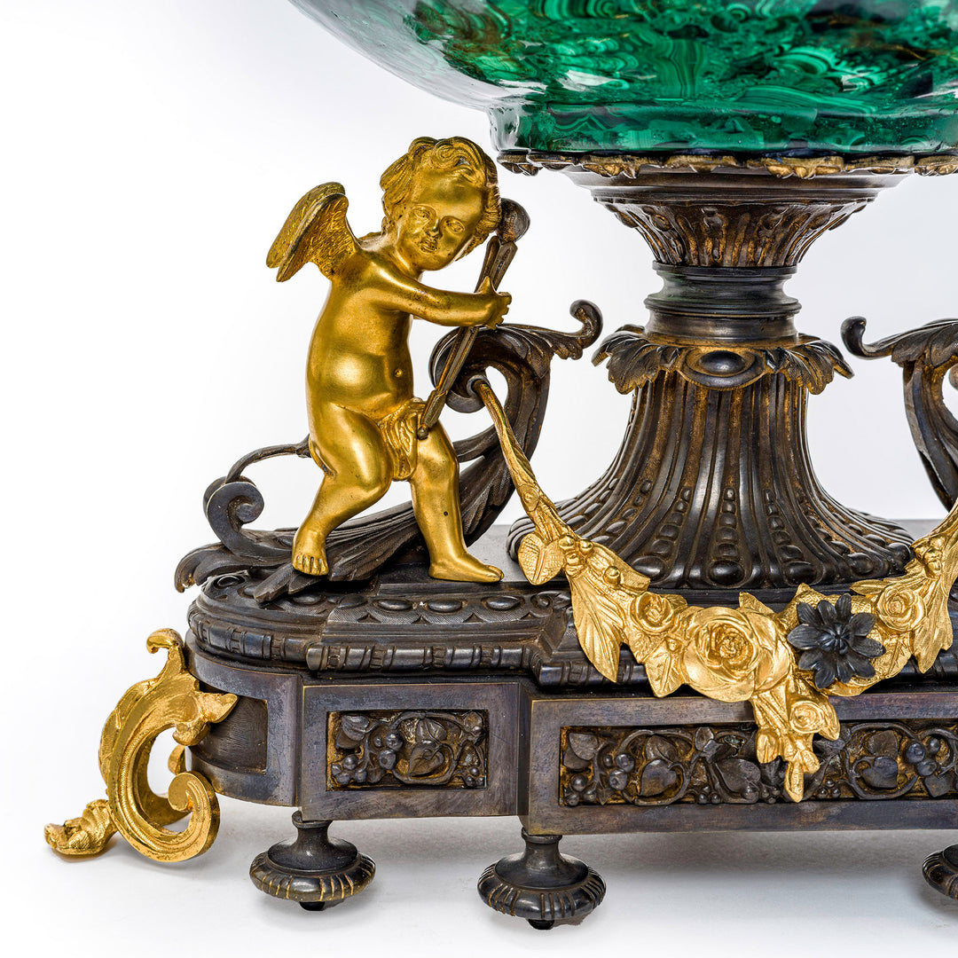 Antique malachite bowl held by golden cherubs, perfect for collectors.