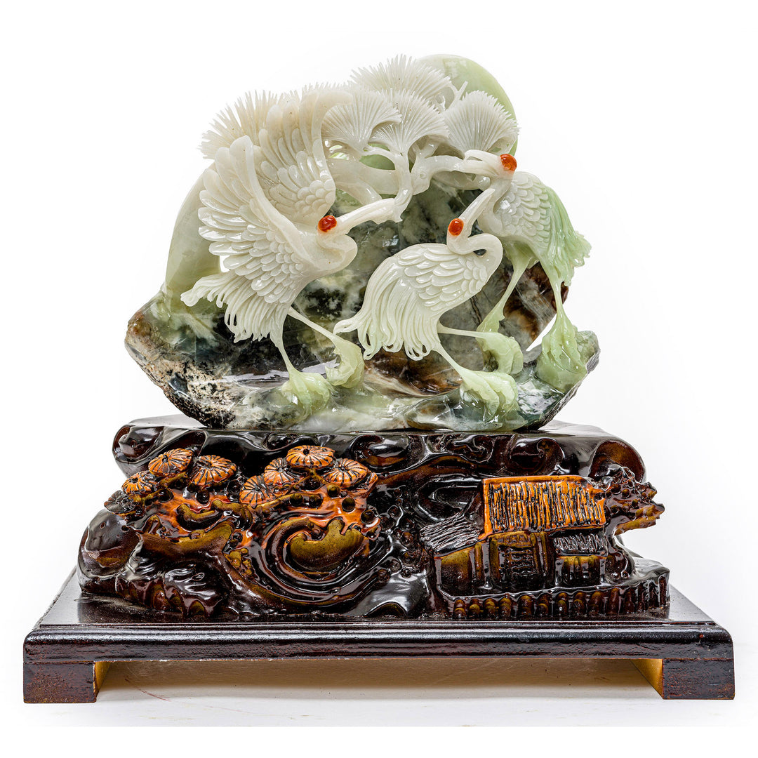 Hand-carved agate sculpture of three cranes on a rock ledge.