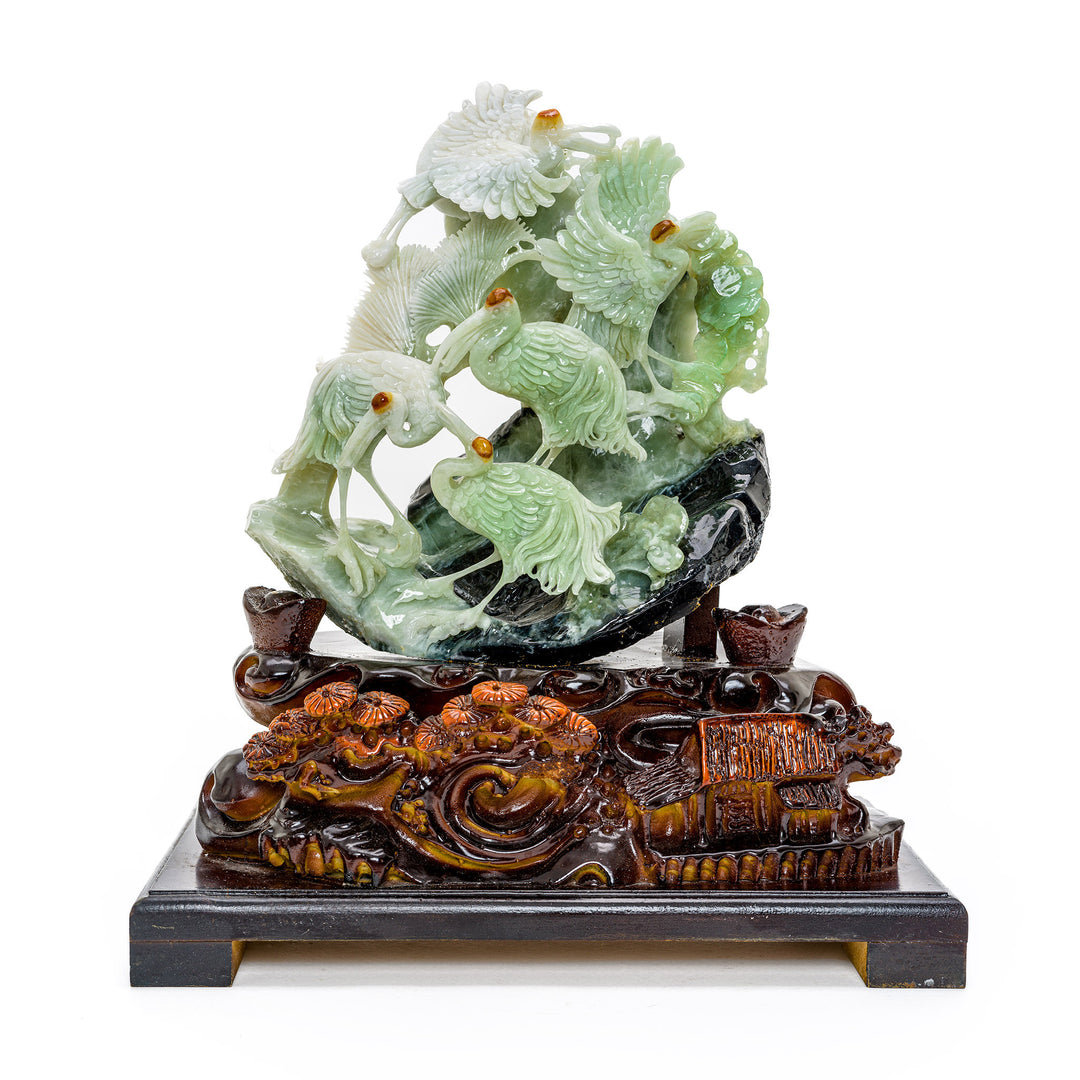 Hand-carved agate sculpture of cranes on a hillside with wooden base.