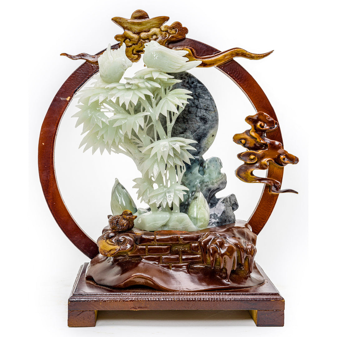 Agate sculpture of carved bamboo shoots with birds on a wooden base against a moon backdrop.