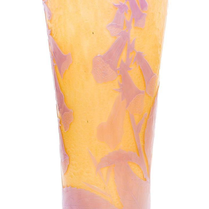 Daum glass vase with pink leaves on a textured yellow background.