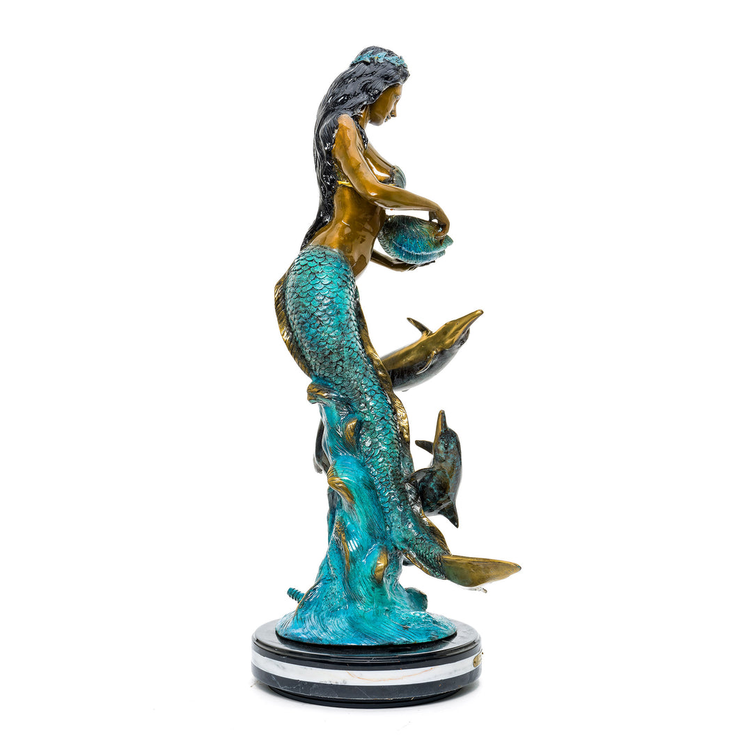 Bronze sculpture of a mermaid and dolphins on a solid base.