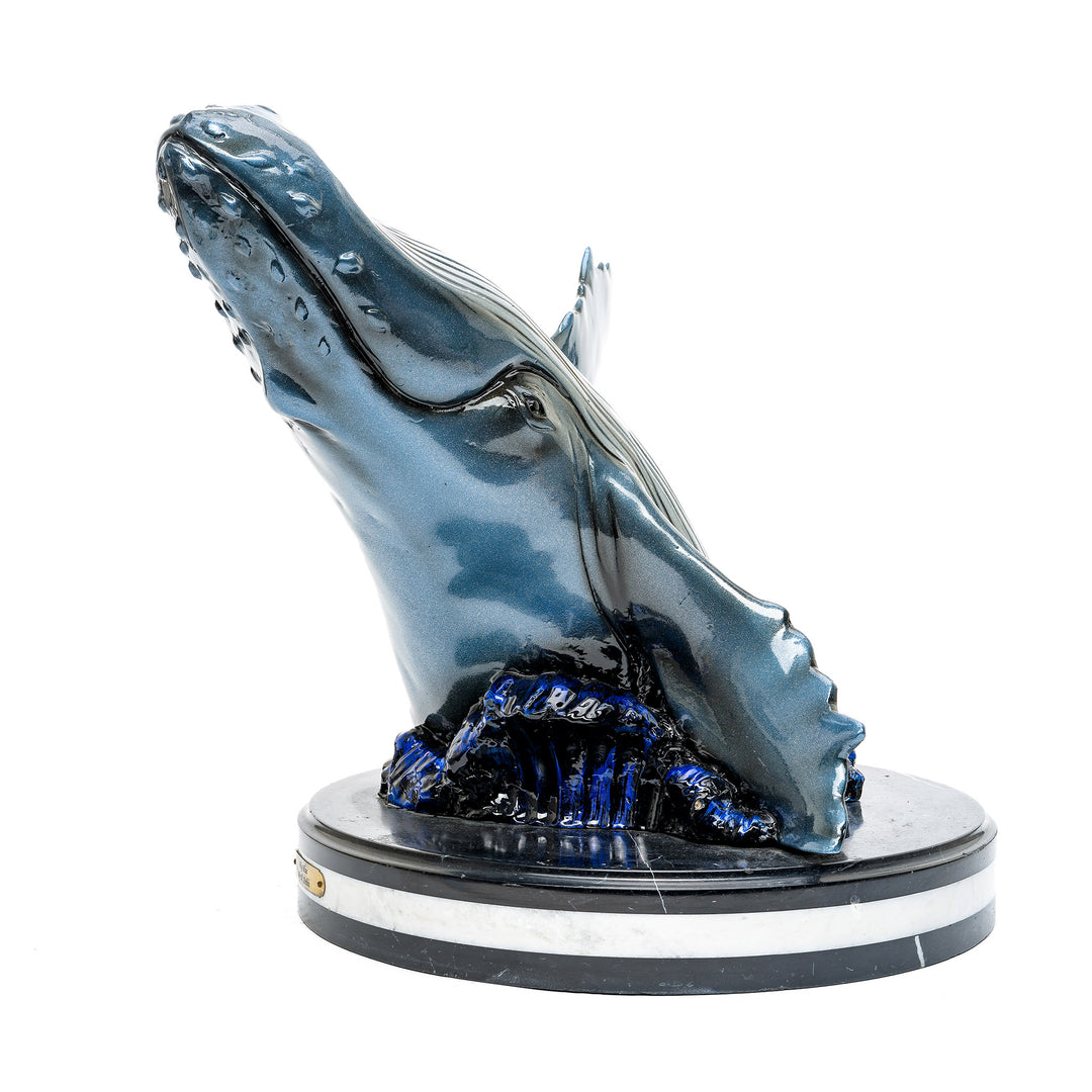 Dynamic whale breaching in a lifelike bronze sculpture on marble base.