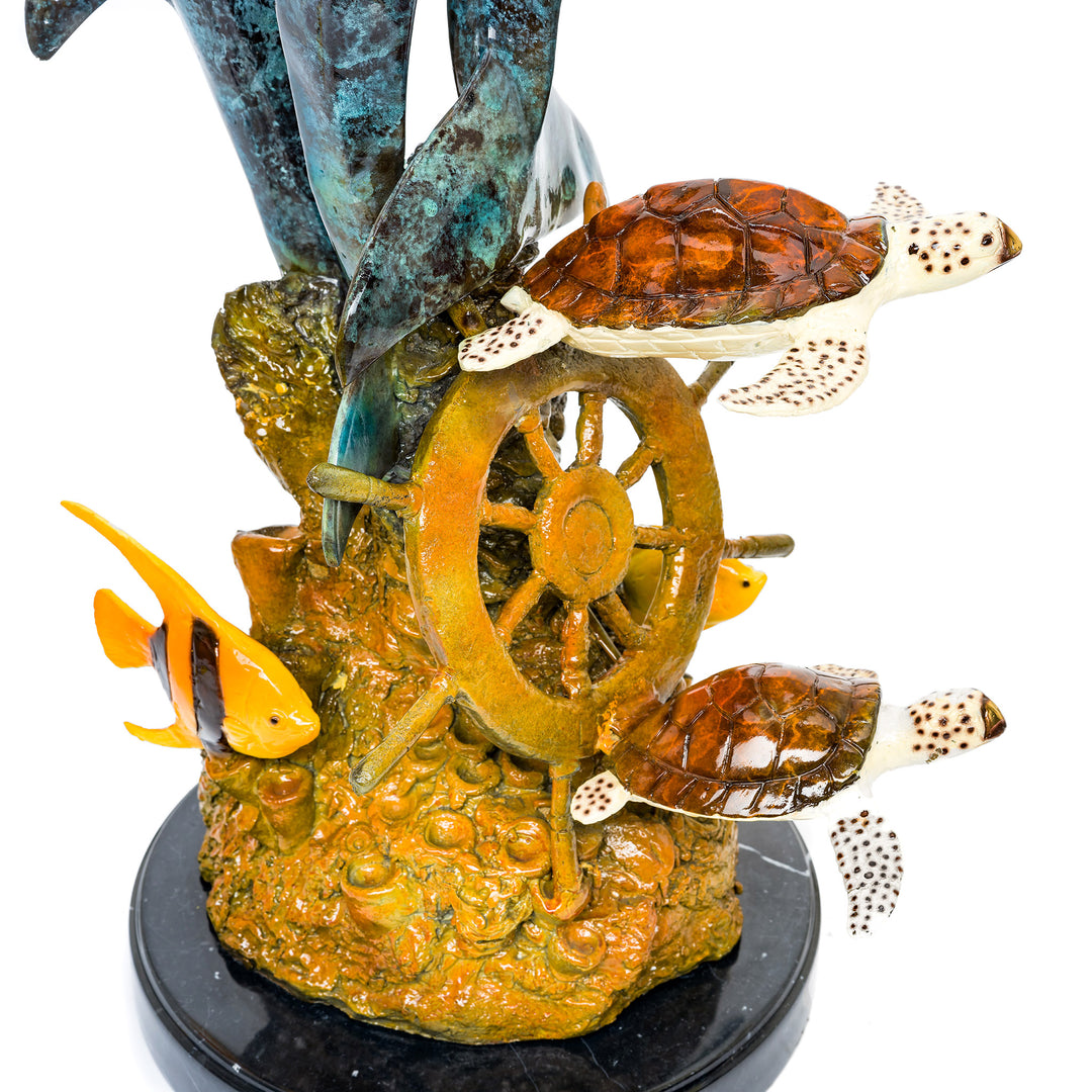 Intricately crafted bronze sculpture of dolphins and a sunken ship’s wheel.