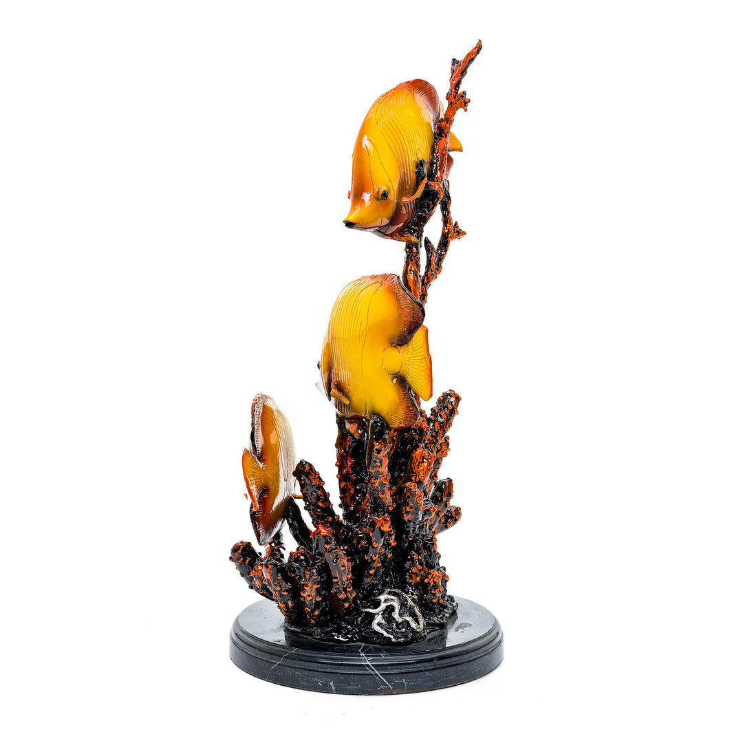 Three fish swimming around coral in a vibrant bronze sculpture.