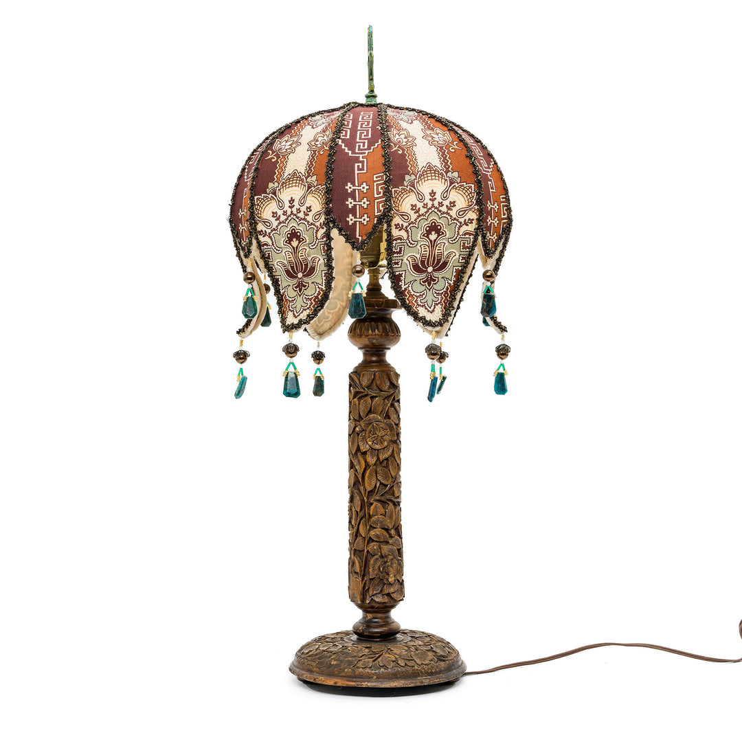 Decorative bronze lamp with warm earth-tone patterns and fringe details