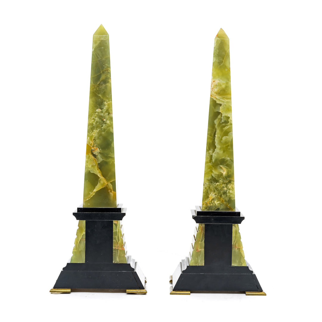 Exquisite onyx obelisks with bronze and gold detailing on black marble bases.