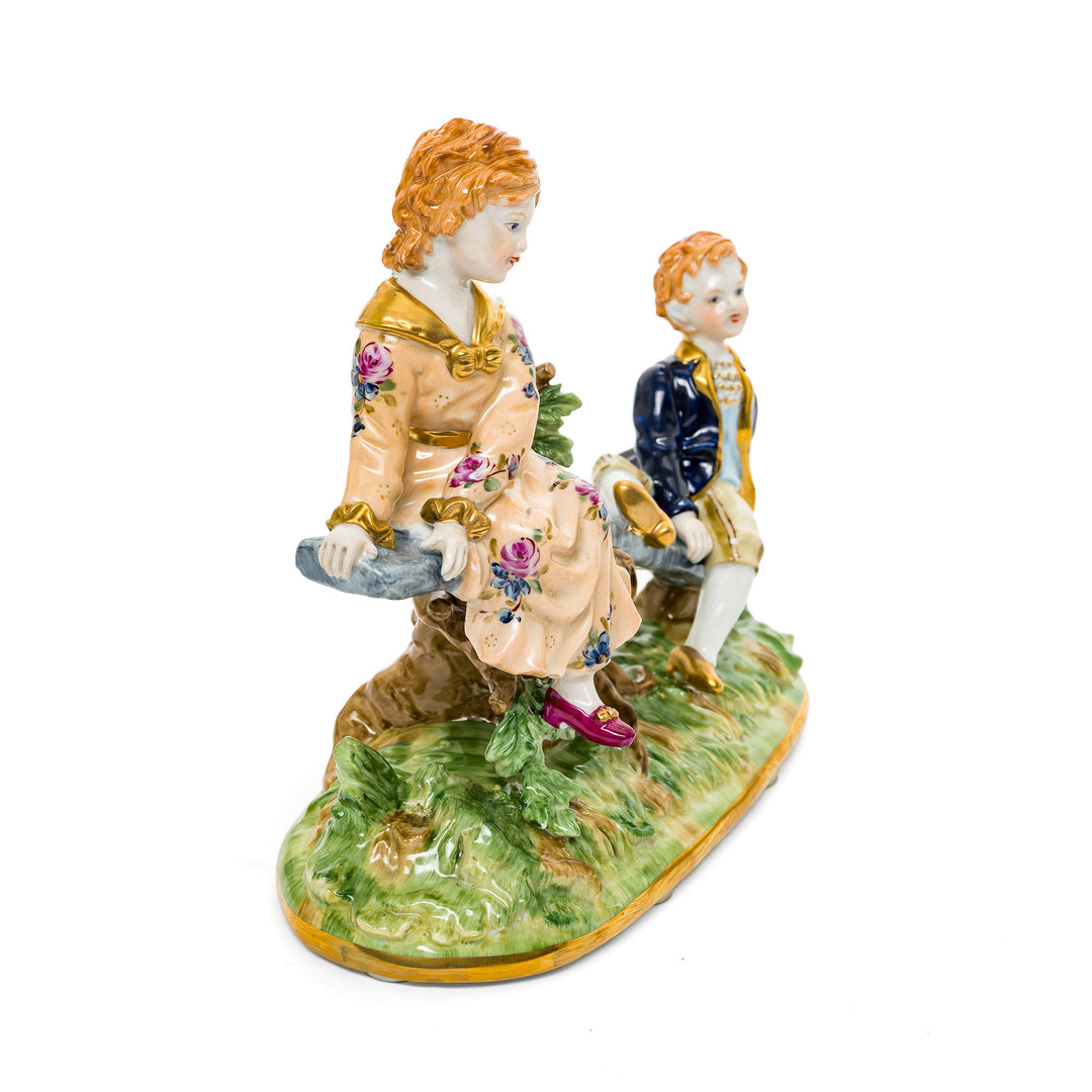 Playful porcelain figurine of children enjoying a seesaw, crafted in Germany.