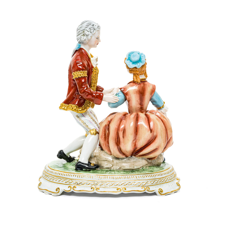 Romantic German porcelain figurine of a couple in a proposal scene with vibrant floral accents.