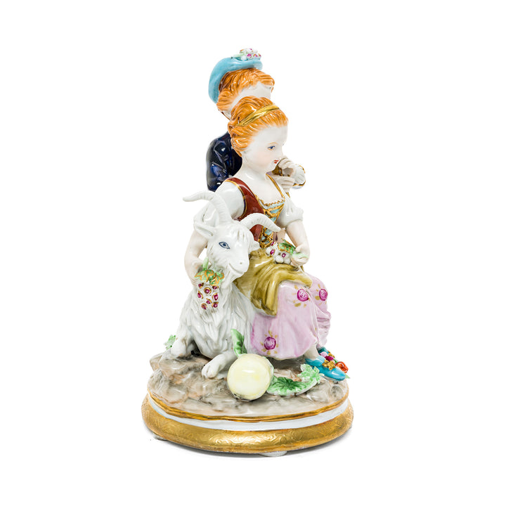 Whimsical German porcelain figurine of children in a meadow, with vibrant hand-painted details and a gold-trimmed base.