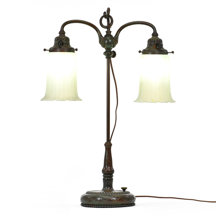 Tiffany double student lamp with green and red highlights, featuring two vertically ribbed bell shaped shades and a ruffled rim base, signed on the underside.